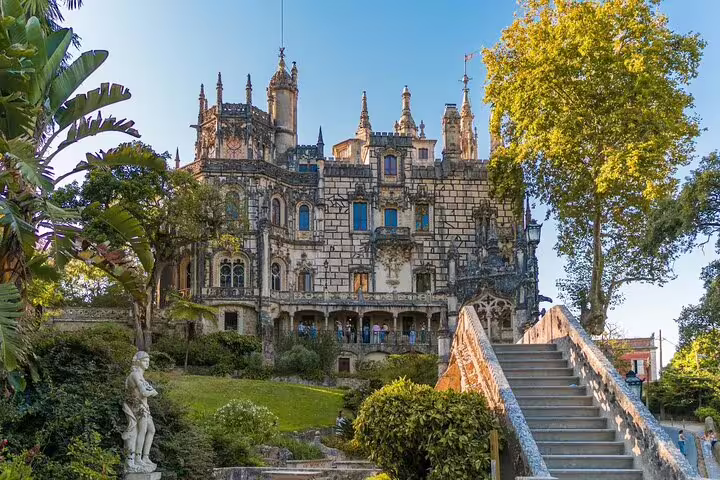Historic Sintra palace surrounded by lush gardens, featuring intricate architecture, part of a guided half-day tour with tickets included.