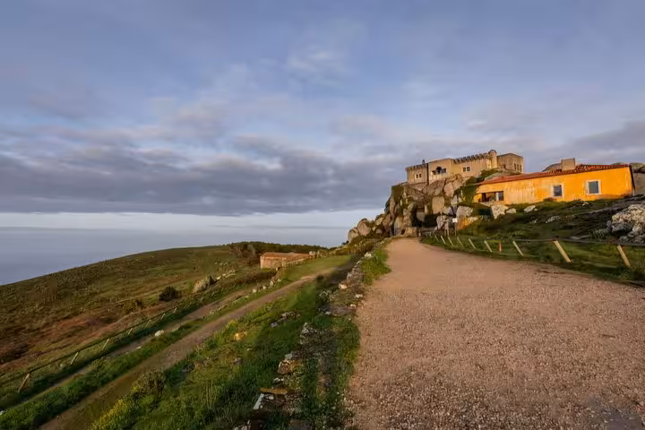 Scenic view of a historic building on a hilltop along the Sintra tour route, under a clear blue sky.