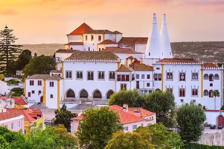 Sunset view of the National Palace of Sintra, showcasing its iconic architecture and vibrant surroundings.