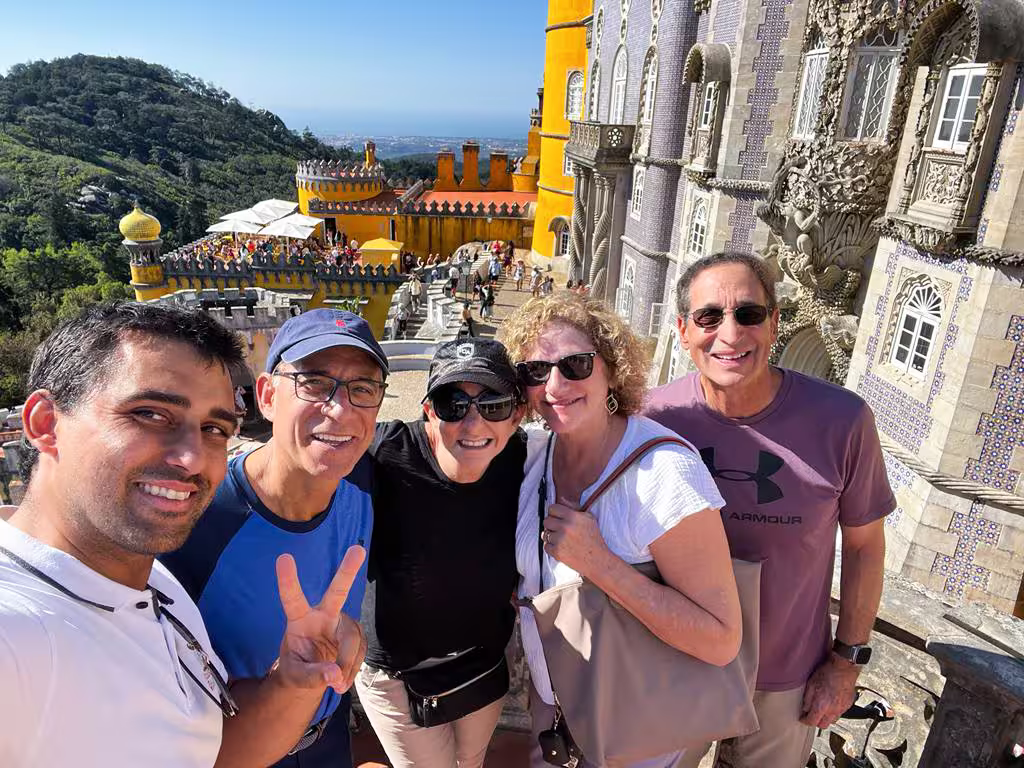 Smiling tourists at Pena Palace with scenic Sintra landscape in the background, perfect for private tour.