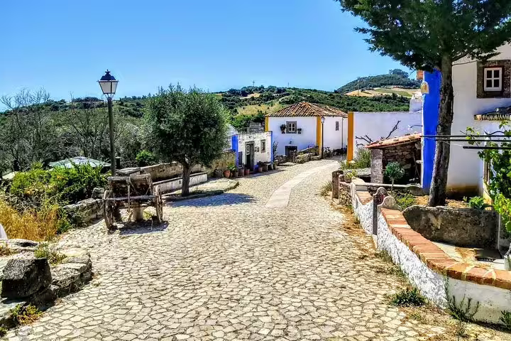 Charming cobblestone street in a quaint Portuguese village near Sintra, showcasing traditional architecture and lush landscapes.