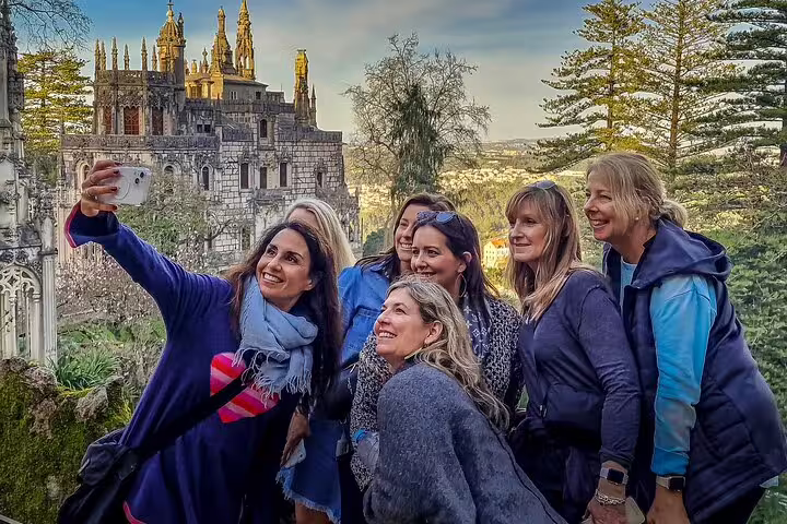 Group of tourists taking a selfie with the stunning backdrop of Sintra's historic architecture during a private tour from Lisbon.