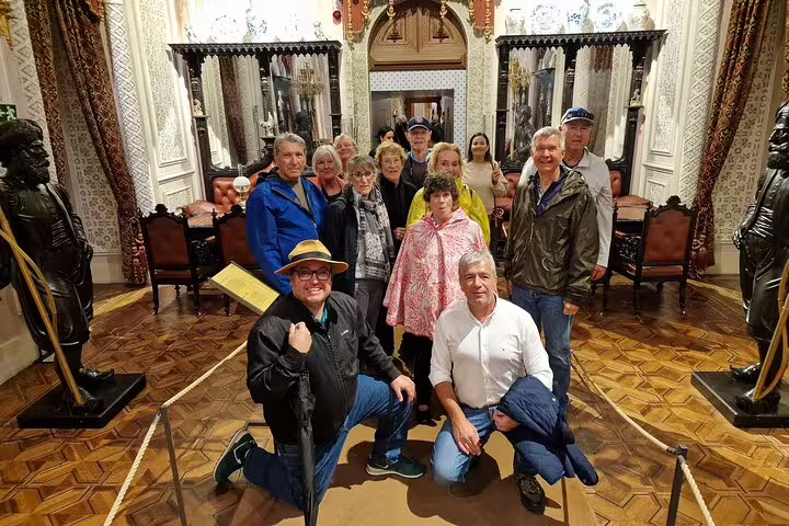Group of tourists enjoying a private Sintra tour with tickets to monuments, starting from Lisbon, inside a historic palace.