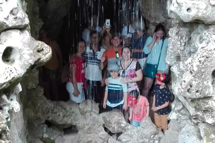 Tourists enjoy a scenic grotto experience during the Sintra, Roca, and Cascais full-day private tour, capturing memorable moments.