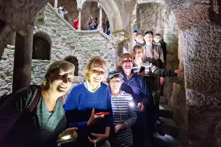 Tourists explore the mystical stone corridors on the Sintra, Roca, and Cascais full-day private tour with Pena tickets.