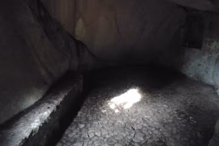 Dimly lit stone chamber with textured cobblestone floor, part of the mysterious landmarks in Sintra.