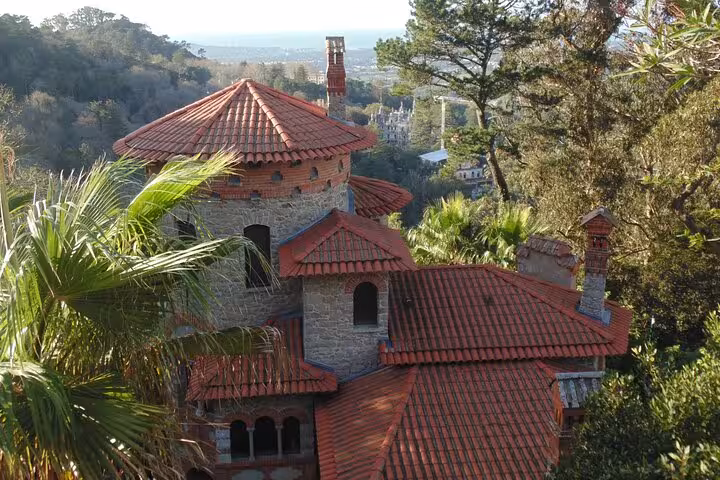 Charming stone villa with red-tiled roofs nestled among lush greenery and trees in the hills of Sintra.
