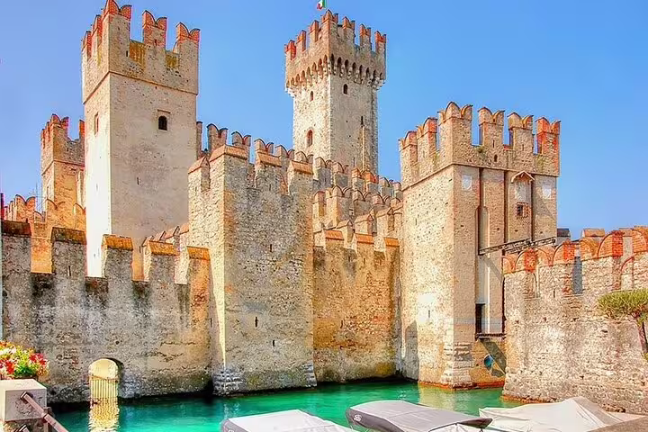 Stunning view of Sirmione Castle with boats on the turquoise water, a highlight of the Franciacorta private tour.