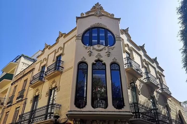 Elegant Art Nouveau building in Sitges with ornate balconies and large windows on a sunny day.