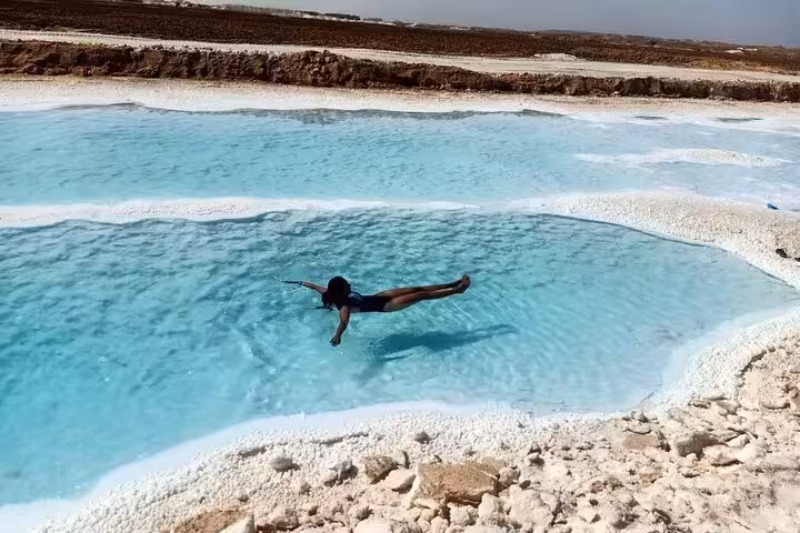 Traveler floating in Siwa Oasis salt lake pools on a one-day trip from Marsa Matrouh, Egypt desert tour