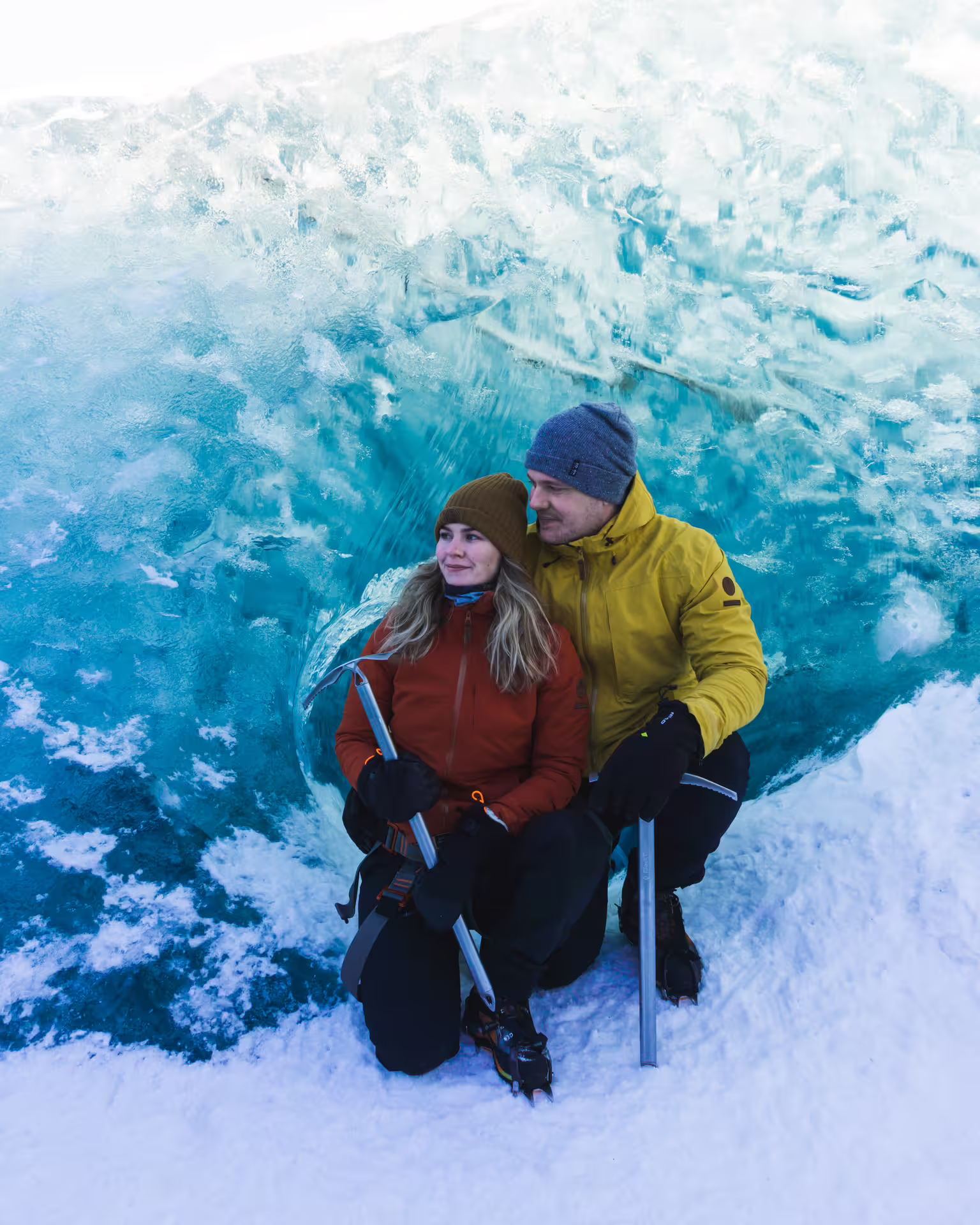 Couple sitting inside a stunning blue ice cave during a Skaftafell glacier hike tour in Iceland