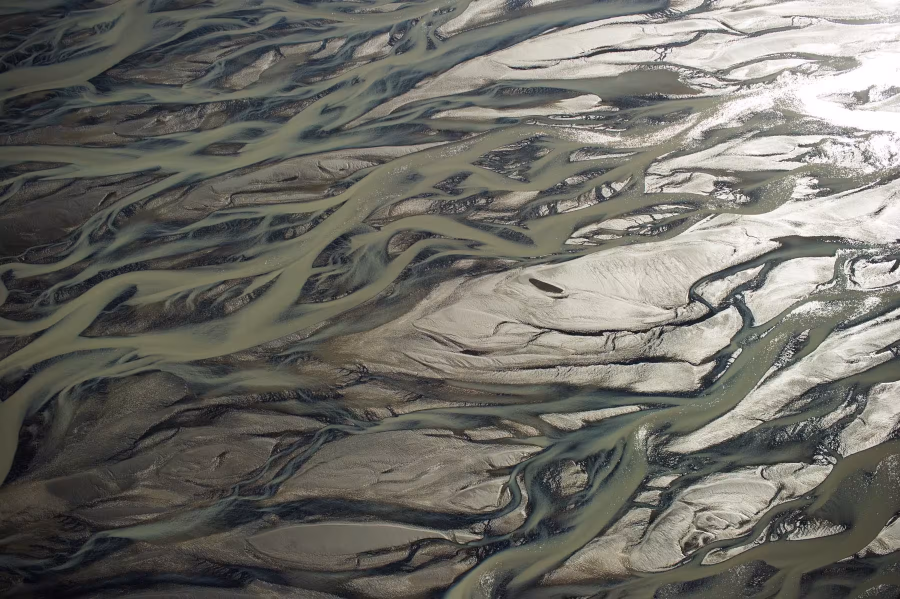 Aerial view of braided glacial riverbeds in Skaftafell, Iceland, with silty green and silver waterways