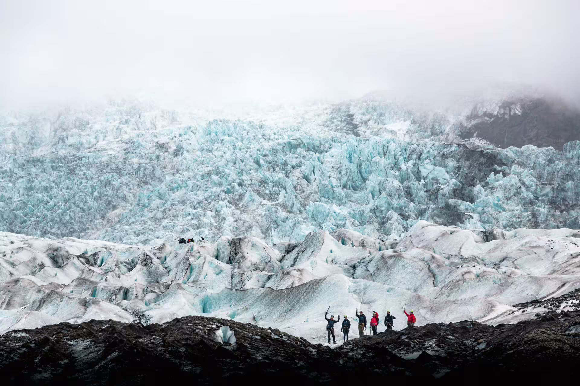 Group of hikers with ice axes standing on Skaftafell glacier with towering blue ice formations behind them