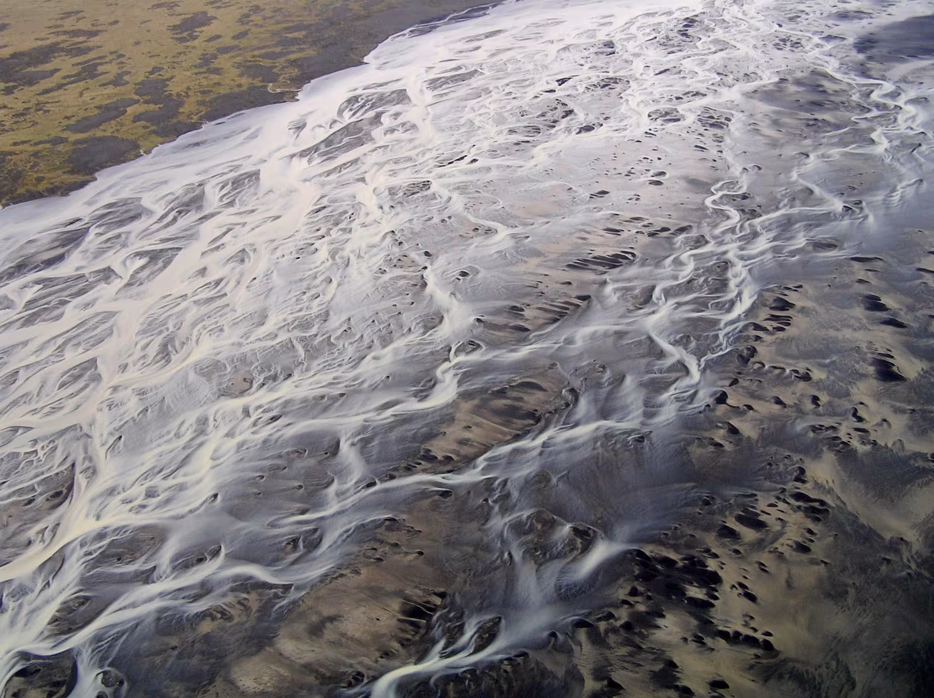 Aerial view of braided glacial rivers flowing across Iceland's black sand plains near Skaftafell