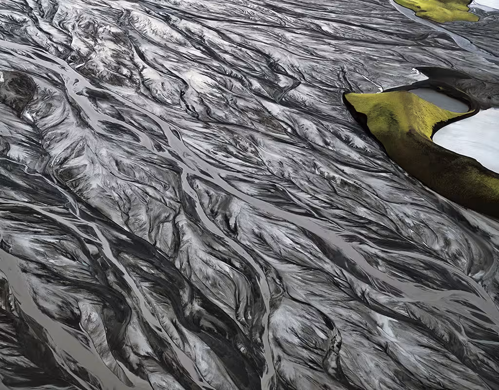 Aerial view of black sand plains with braided glacier rivers and green moss island near Skaftafell Iceland
