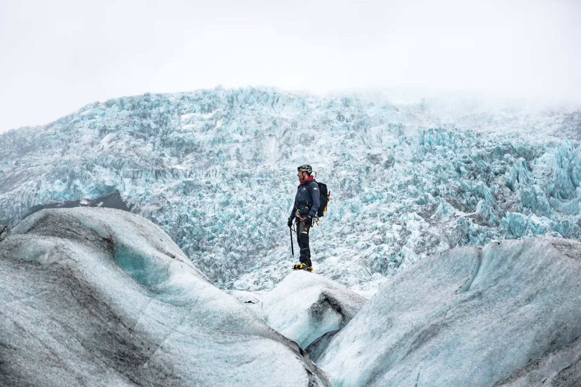 Climber with crampons and ice axe standing on Skaftafell glacier with jagged blue ice formations