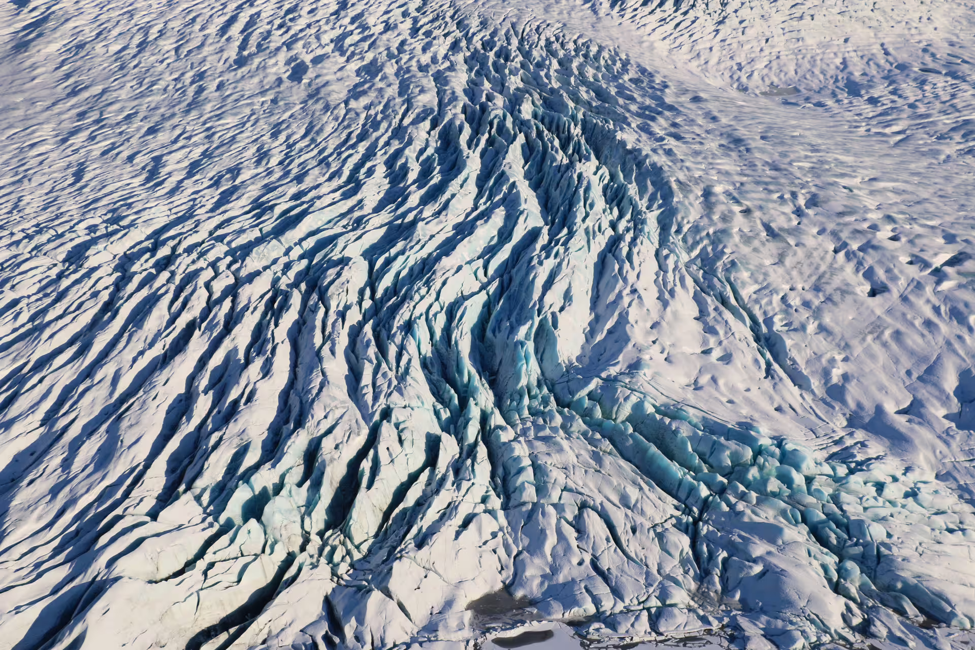 Aerial view of heavily crevassed glacier ice with blue cracks and snow-covered plains at Skaftafell