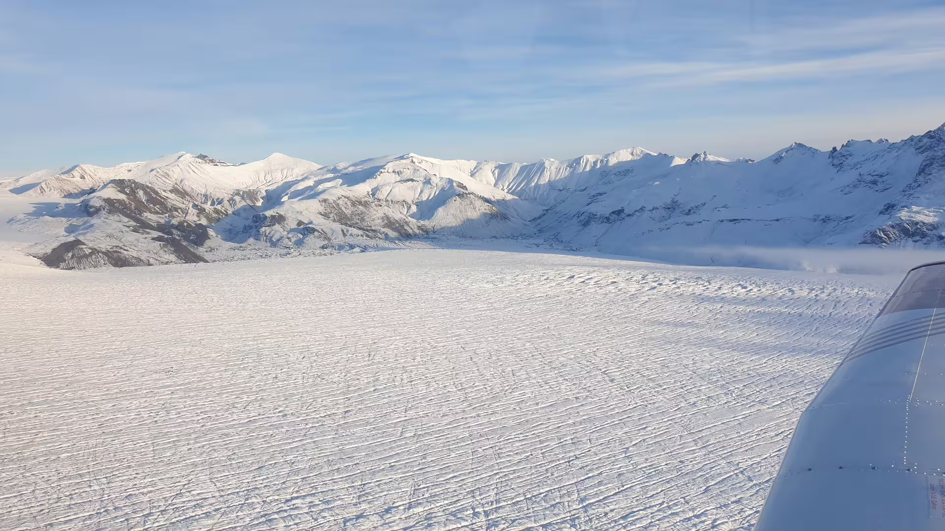 Aerial view of vast glacier snowfield surrounded by snow-capped mountains near Skaftafell, Iceland