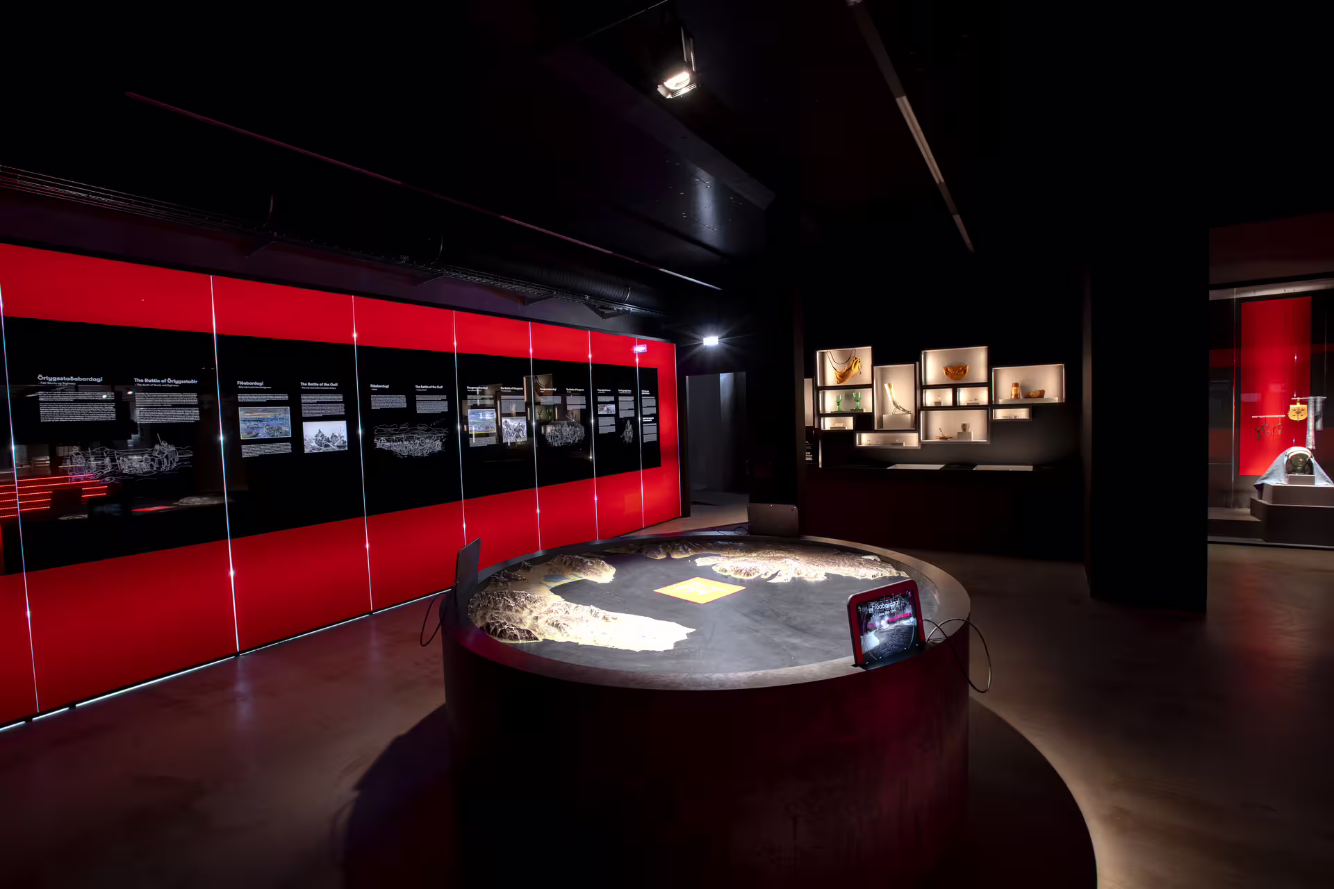 Viking history museum exhibit with red display panels, circular artifact table, and illuminated wall cases in Skagafjordur