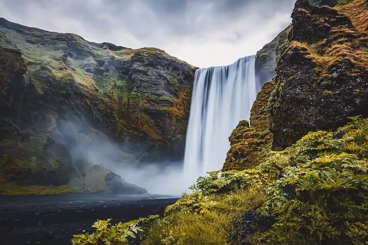 Skógafoss waterfall cascading down mossy cliffs on Iceland's South Coast with mist rising
