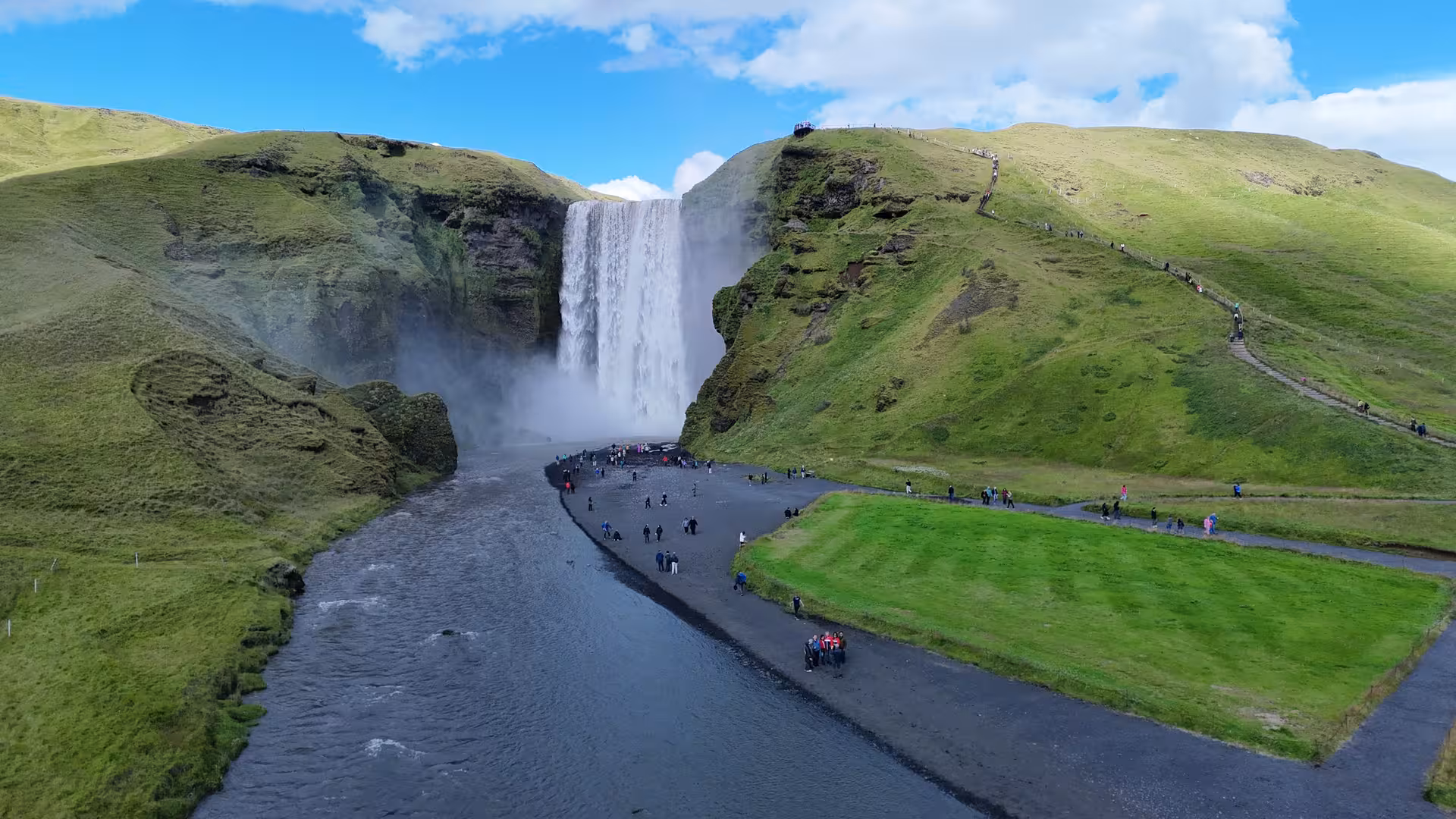 Aerial view of Skógafoss waterfall with tourists on Iceland's South Coast on a sunny day