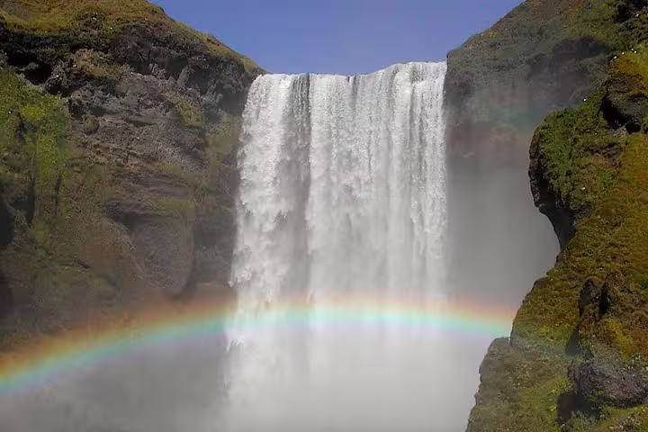 Massive Skógafoss waterfall with double rainbow in Iceland's South Coast landscape