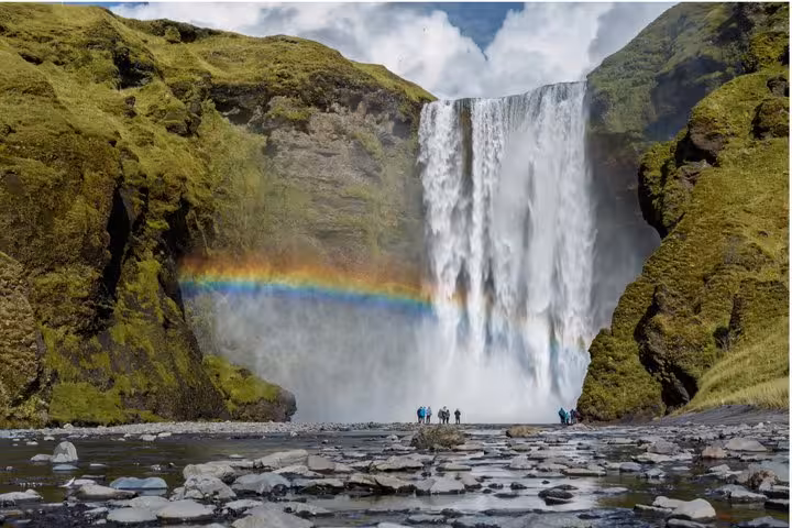 Skógafoss waterfall with rainbow and tourists on Iceland's South Coast near Reykjavik