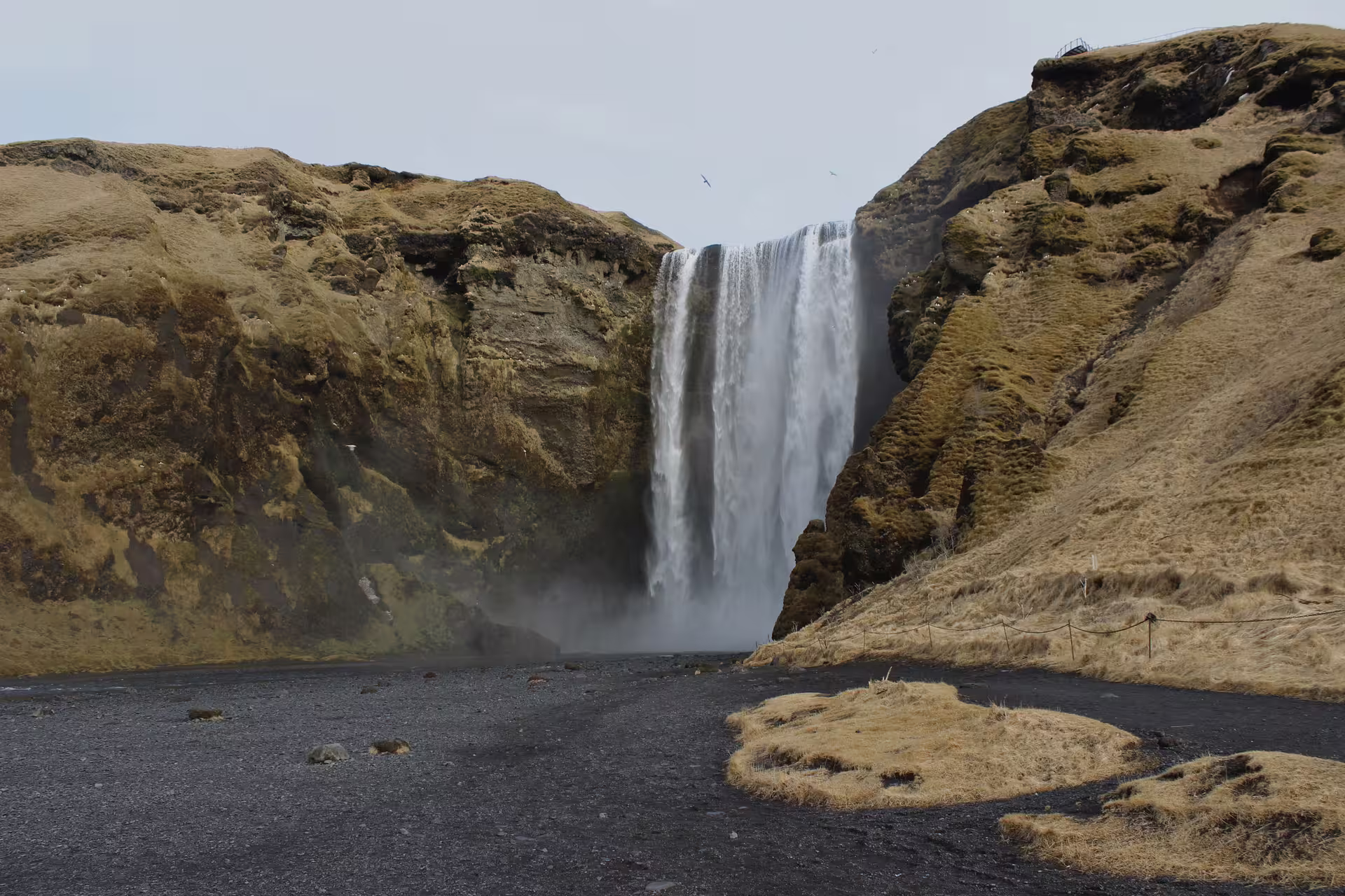 Skógafoss waterfall cascading down volcanic cliffs on Iceland's South Coast with black sand foreground