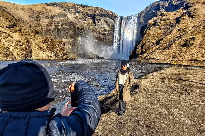 Tourist posing in front of Skógafoss waterfall on Iceland's South Coast tour