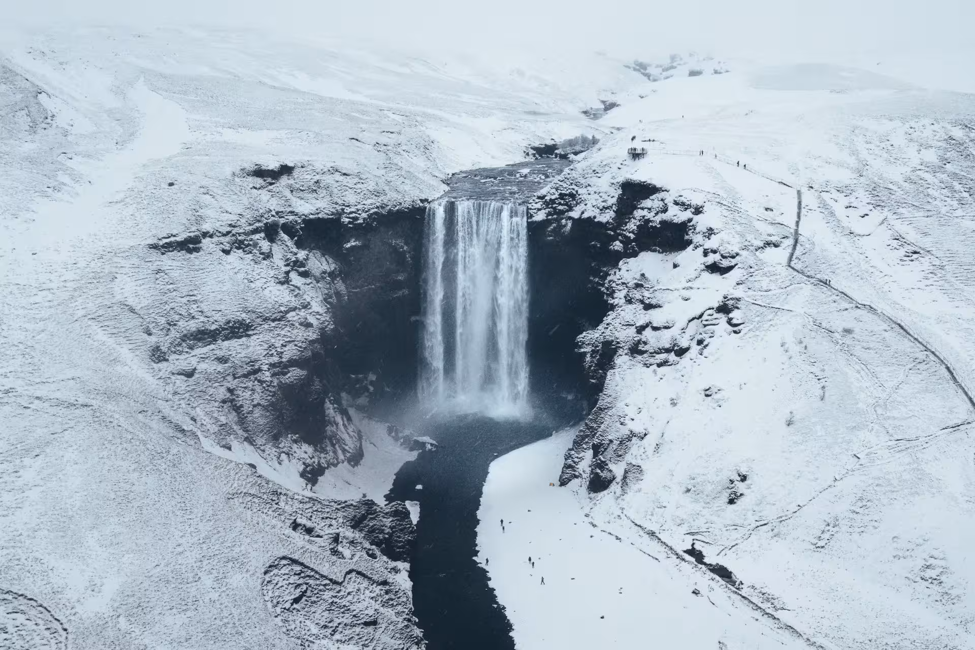 Aerial view of Skógafoss waterfall cascading into snowy canyon on Iceland's South Coast in winter