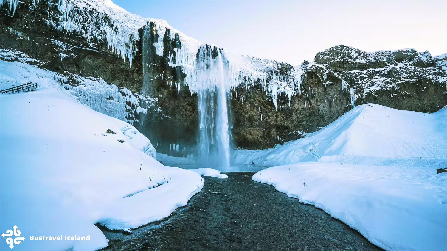 Skógafoss waterfall surrounded by snow, ice, and icicles on Iceland's south coast in winter