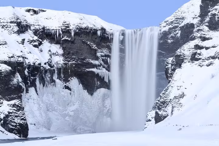 Skógafoss waterfall surrounded by snow and ice formations on Iceland's South Coast in winter