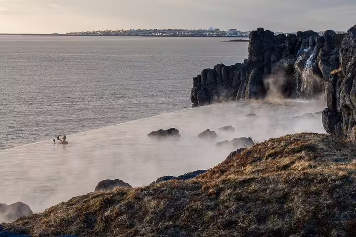 Steaming geothermal Sky Lagoon infinity pool beside volcanic cliffs with ocean view in Iceland