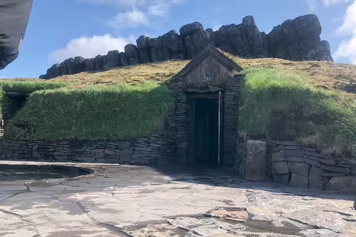 Traditional Icelandic turf house entrance with stone walls and grass roof at Sky Lagoon
