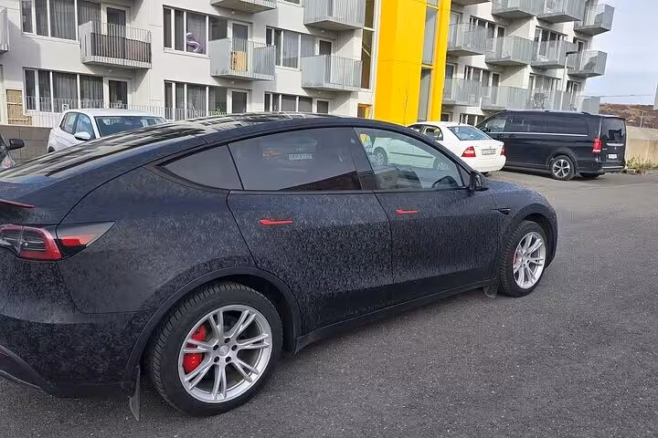 Stylish black vehicle ready for Sky Lagoon private transfers, parked outside modern Reykjavik buildings.
