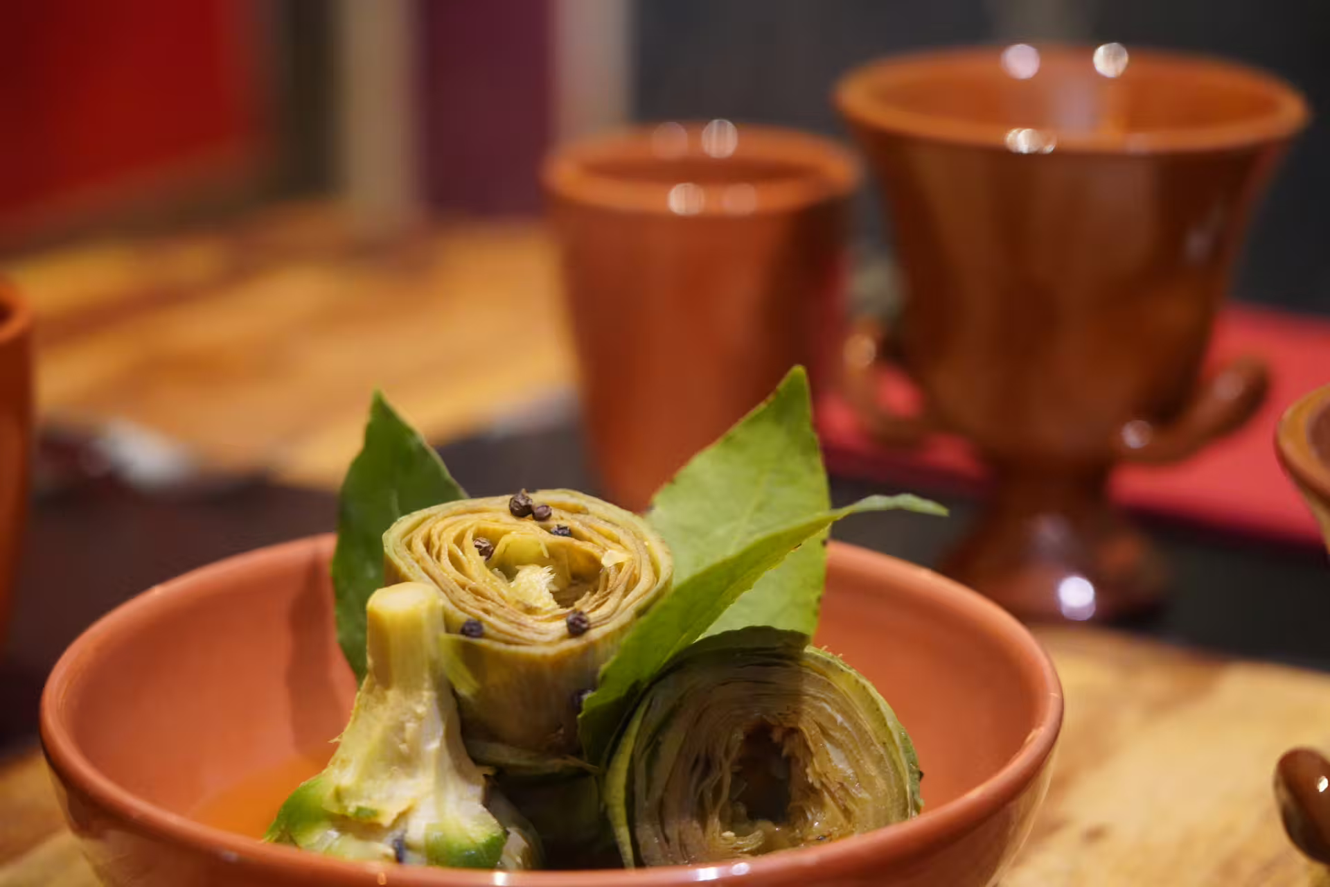 Slow-cooked artichokes with bay leaves in rustic terracotta bowls, recreating authentic ancient Roman lunch in Pompeii