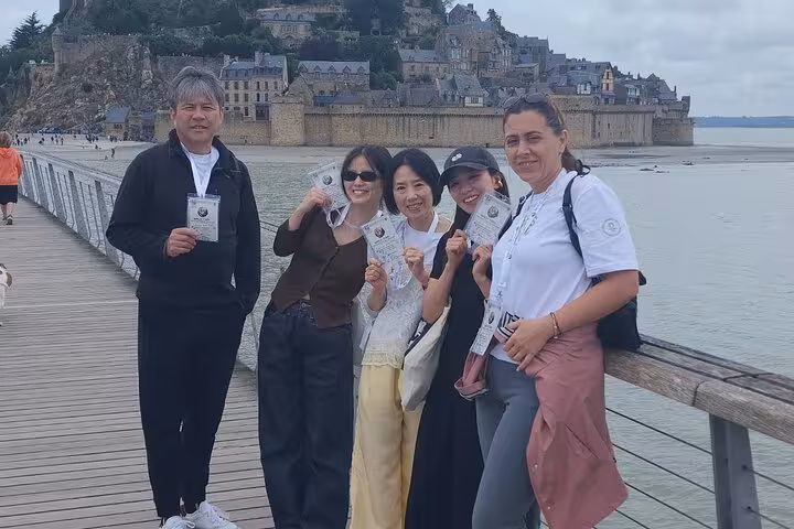 Small group travelers on Mont Saint Michel boardwalk, Normandy, enjoying luxury van day trip from Paris