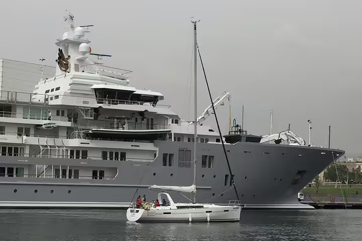 Small group enjoying a 2-hour cruise with food and drinks on a sleek yacht in a serene harbor setting.