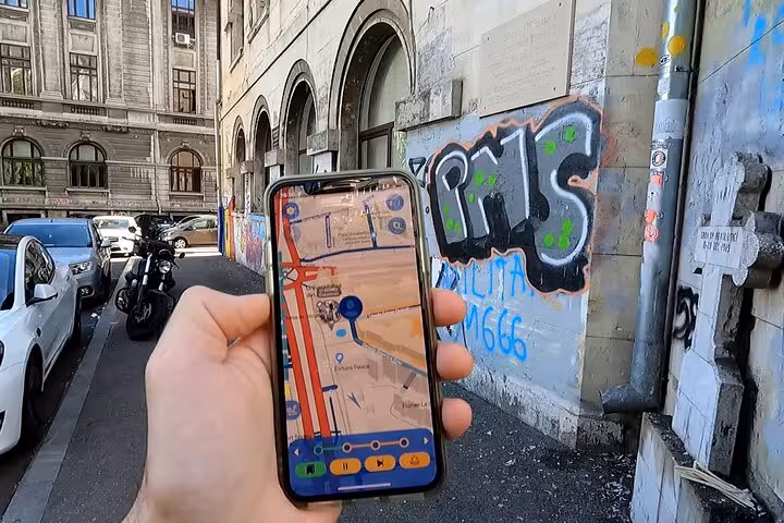 Hand holding a smartphone displaying an interactive map during the Bucharest 1989 Revolution self-guided walking tour