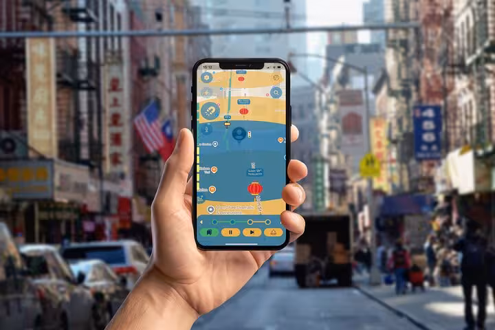 Hand holding a smartphone with a tour map app navigating the vibrant streets of NYC Chinatown walking tour