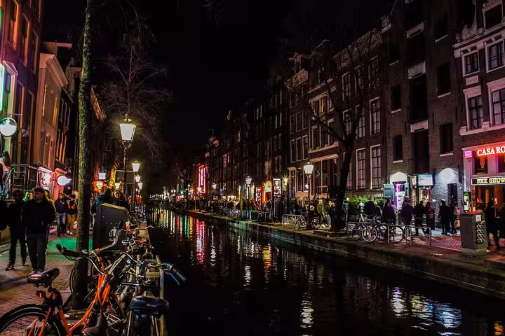 Hands holding a smartphone with a navigation app while exploring Amsterdam Red Light District canal on a self-guided tour