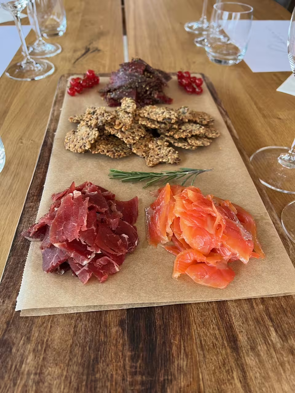 Hidden Fjord Escape charcuterie board with smoked salmon, cured meat, seeded crackers, and red currants on rustic wood table.