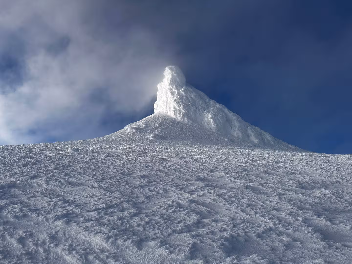 Snow-covered Snaefellsjokull glacier volcano summit peak under deep blue sky with blowing snow