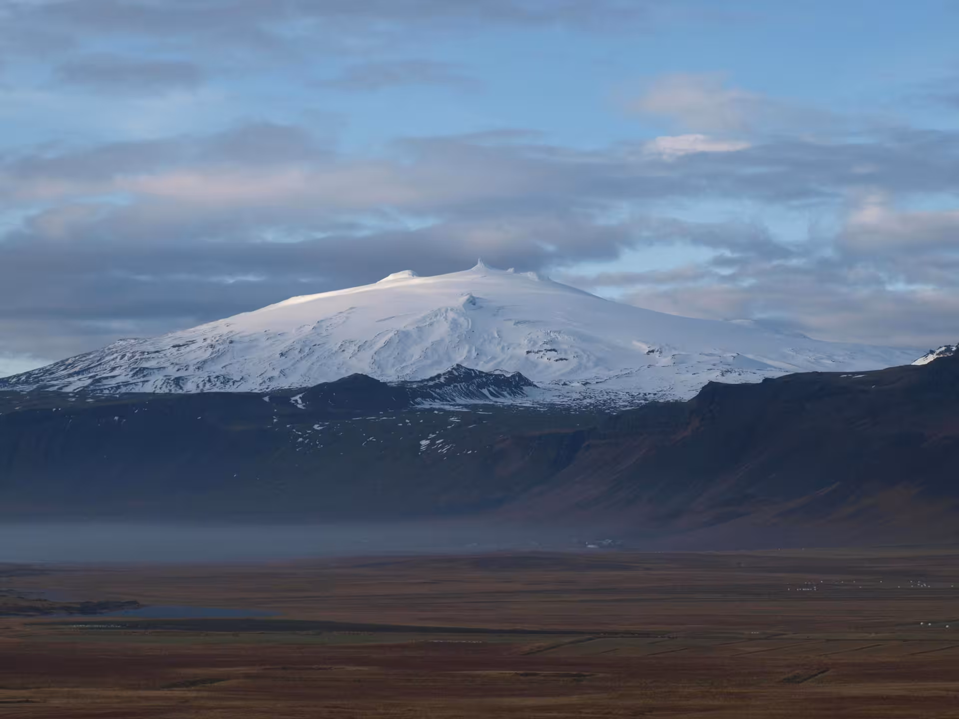 Snow-capped Snæfellsjökull volcano rising above a vast flat lava plain on the Snæfellsnes Peninsula, Iceland