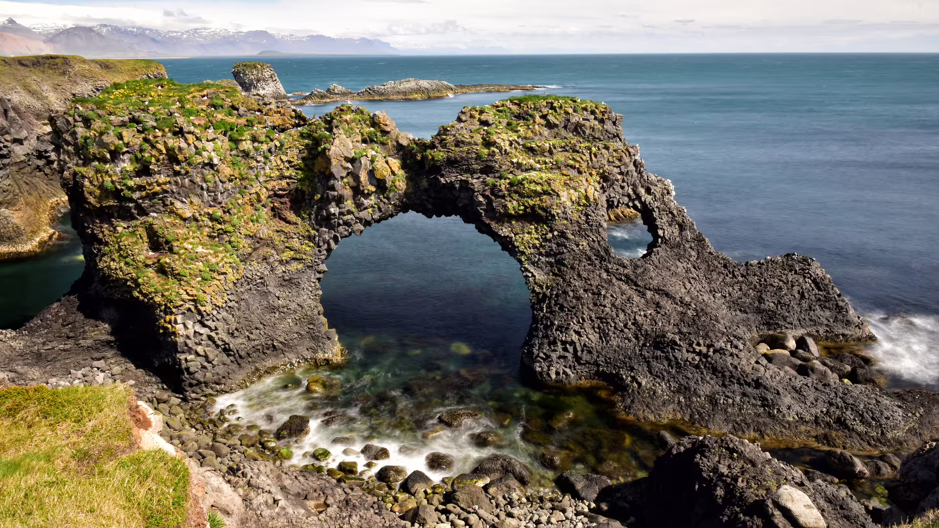 Gatklettur rock arch on Snaefellsnes Peninsula coastline with mossy basalt and ocean views