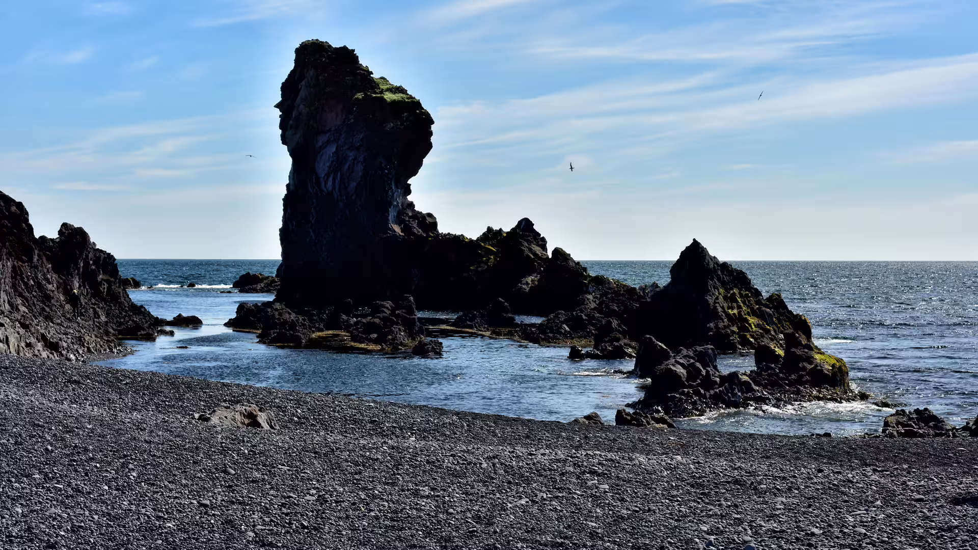 Tall volcanic sea stack on black sand beach at Snaefellsnes Peninsula, Iceland