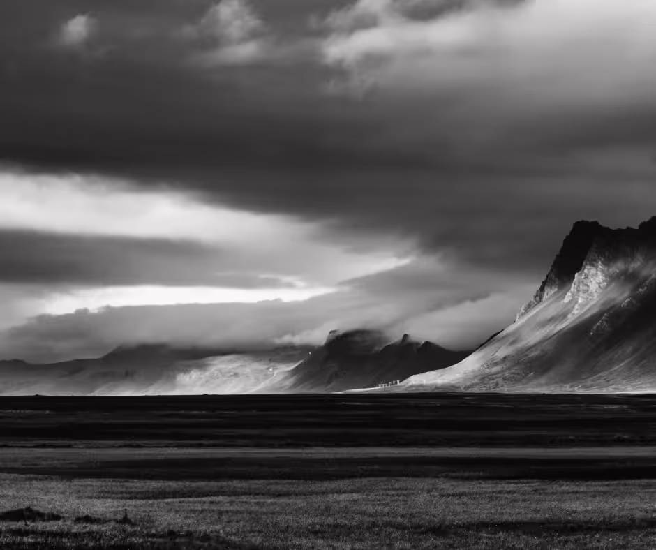 Dramatic black and white landscape with volcanic plains and rugged mountain peaks under stormy skies in Snaefellsnes