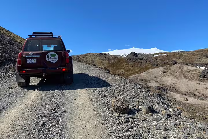 Red 4x4 SUV on gravel road toward Snæfellsjökull glacier on Snaefellsnes Peninsula, Iceland