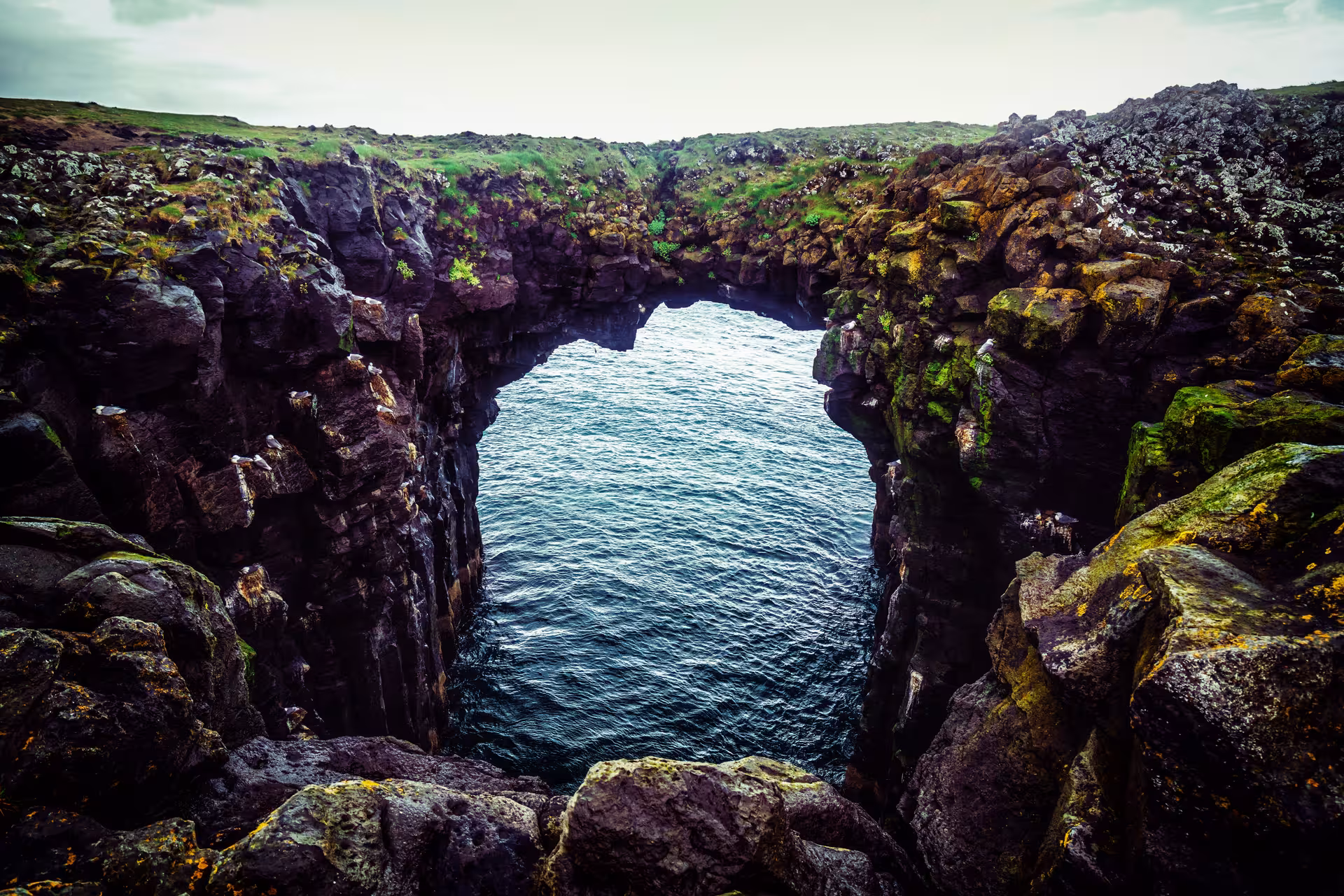 Natural basalt rock arch over dark blue ocean waters at Snaefellsnes Peninsula, Iceland