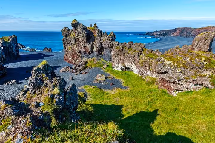 Black volcanic beach and jagged lava rock formations along Snaefellsnes Peninsula coastline, West Iceland